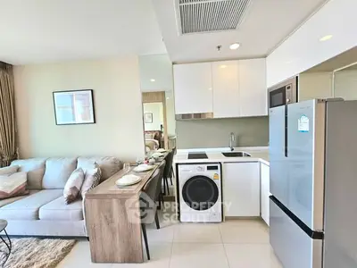 Modern open-plan living room and kitchen with sleek appliances and cozy seating area.