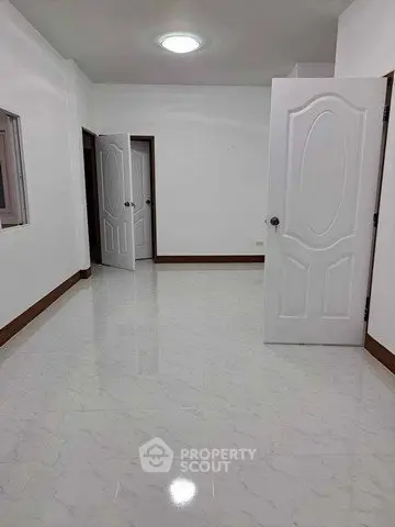 Spacious empty room with white doors and tiled flooring, ideal for customization.