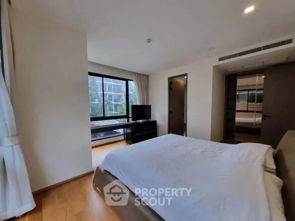 Spacious bedroom with modern decor and large windows offering natural light.