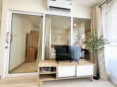 Modern living room with sleek TV stand and glass sliding doors leading to a cozy bedroom.