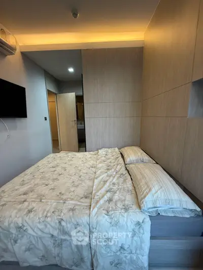 Cozy bedroom with modern design and soft lighting, featuring a comfortable bed and sleek wooden paneling.