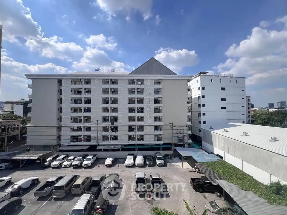 Spacious apartment building with ample parking and clear blue skies, ideal for urban living.