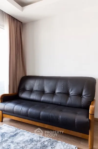 Stylish living room with modern black leather sofa and elegant curtains.