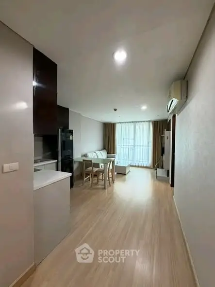 Modern open-plan living room with dining area and large windows in a stylish apartment.