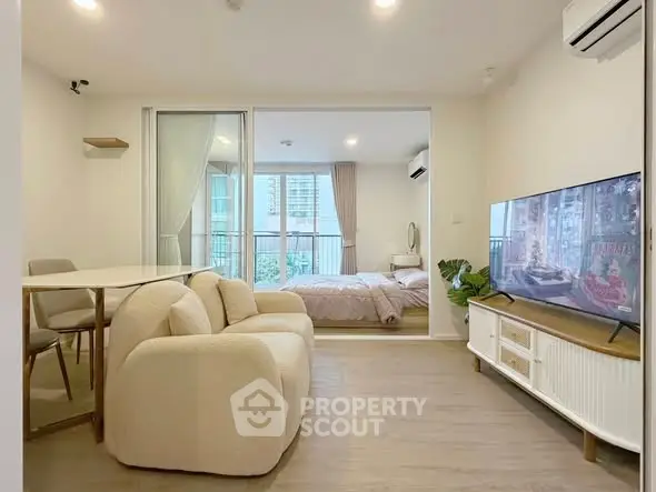 Modern open-plan living room with cozy seating and bedroom view