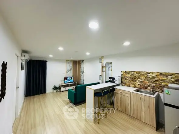 Modern open-layout living room and kitchen with stylish decor and ample lighting.