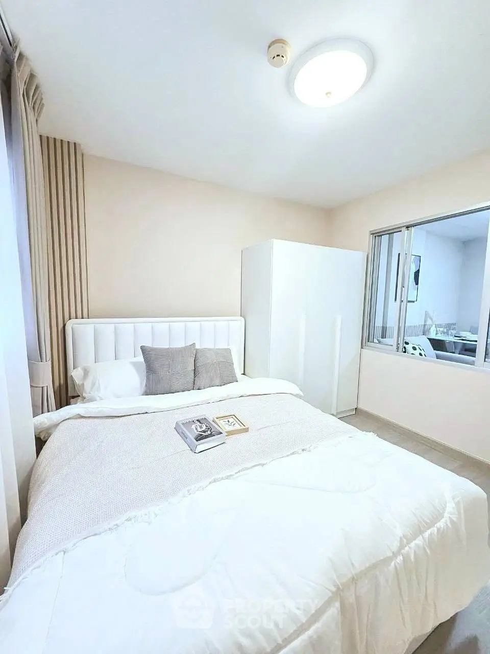Cozy bedroom with modern decor and ample natural light, featuring a comfortable bed and sleek wardrobe.