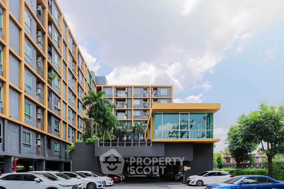 Modern apartment building with parking area and lush greenery, showcasing urban living with convenience and style.
