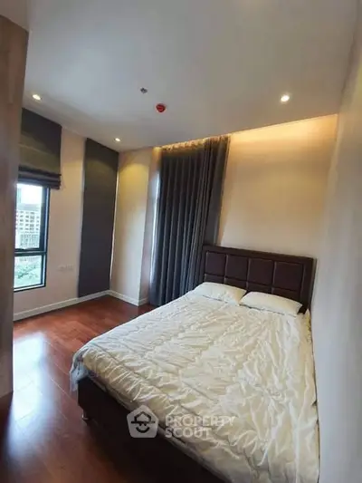Spacious bedroom with large windows and elegant curtains in modern apartment.