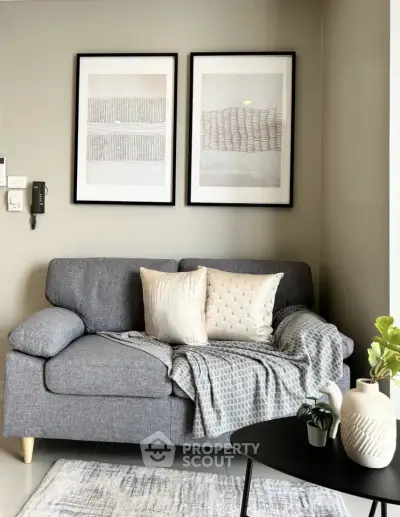 Stylish living room with modern gray sofa, elegant decor, and framed art on the wall.