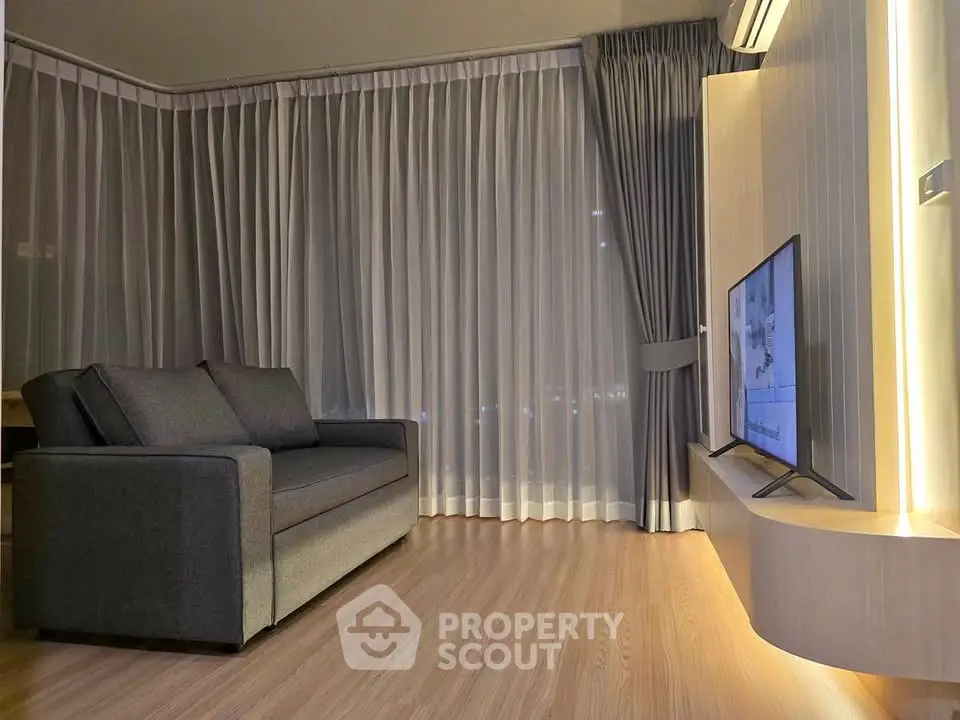 Modern living room with sleek sofa and wall-mounted TV, featuring elegant floor-to-ceiling curtains.