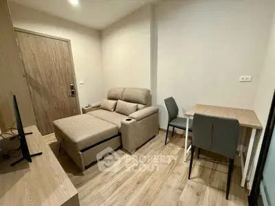 Cozy living room with modern furniture and wooden flooring in a compact apartment.