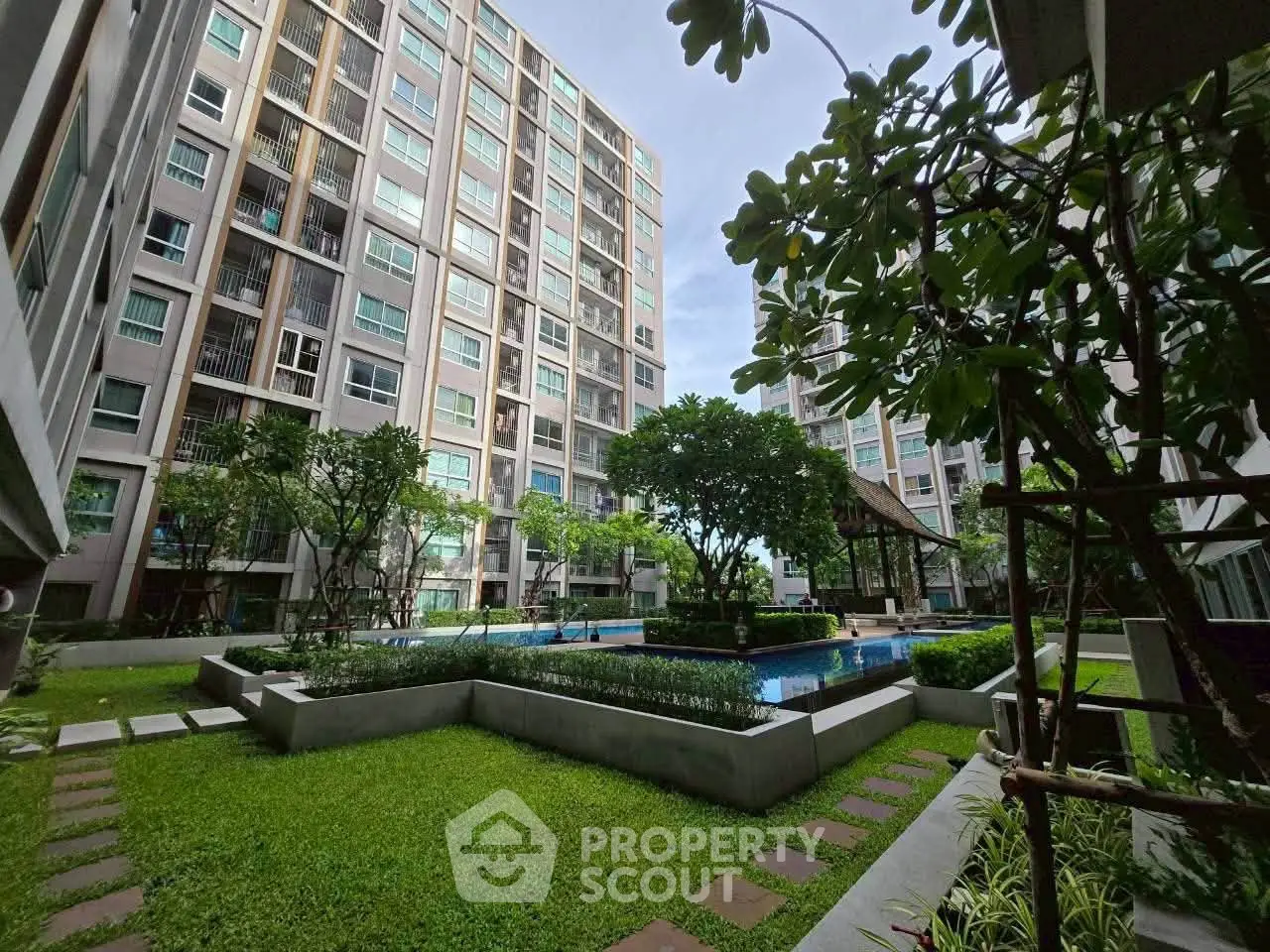 Modern apartment complex with lush garden and pool view