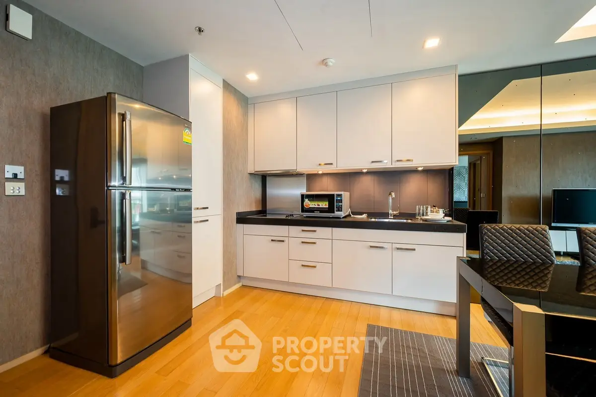 Modern kitchen with sleek appliances and dining area in stylish apartment.