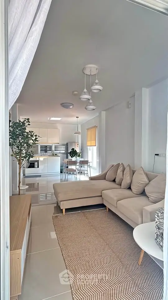 Modern open-plan living room with cozy beige sofa and stylish kitchen area, perfect for contemporary living.