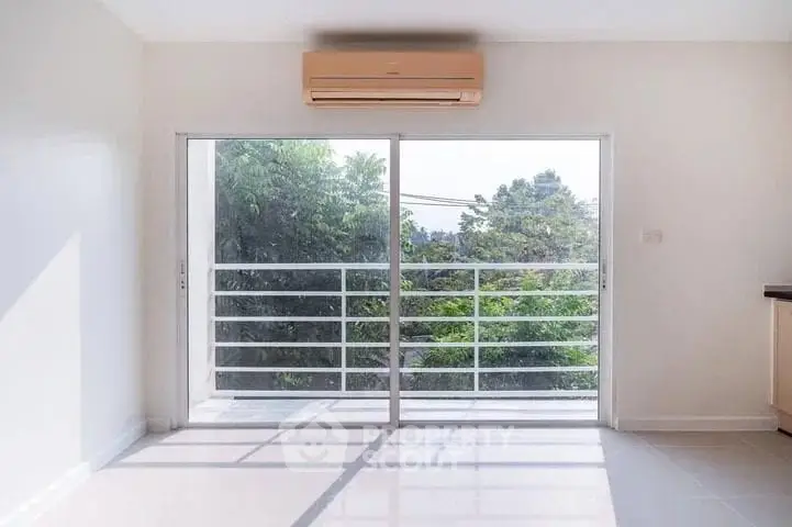 Bright living room with large sliding glass doors leading to a balcony with lush green views.