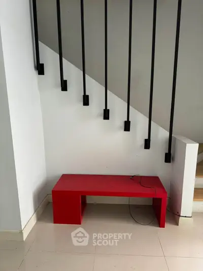 Modern interior with red bench and sleek staircase design