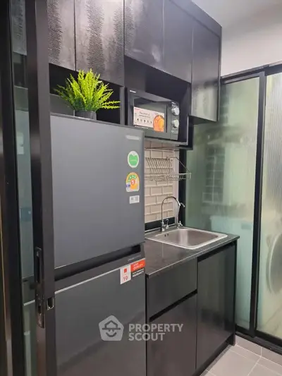 Modern kitchen with sleek black cabinets and stainless steel appliances in a compact layout.