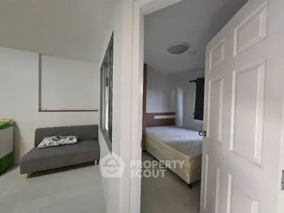 Cozy bedroom with adjacent living area, featuring a comfortable sofa and a neatly made bed, perfect for modern living.