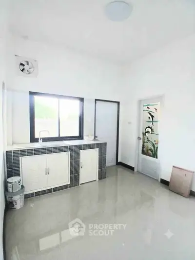 Spacious kitchen with modern design and ample natural light, featuring sleek cabinetry and tiled flooring.