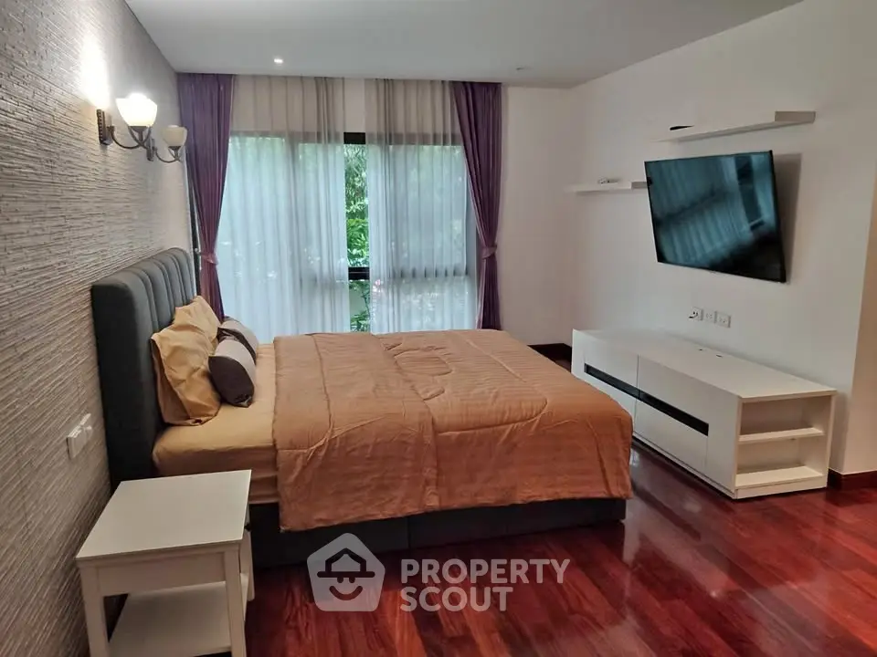 Spacious bedroom with modern decor and large window offering natural light.