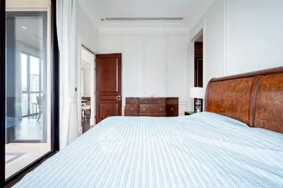 Spacious bedroom with elegant wooden furniture and large window view.