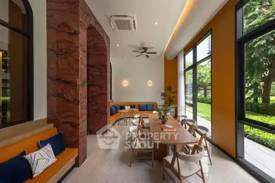 Modern interior with stylish seating and large windows overlooking lush greenery, perfect for relaxation or meetings.