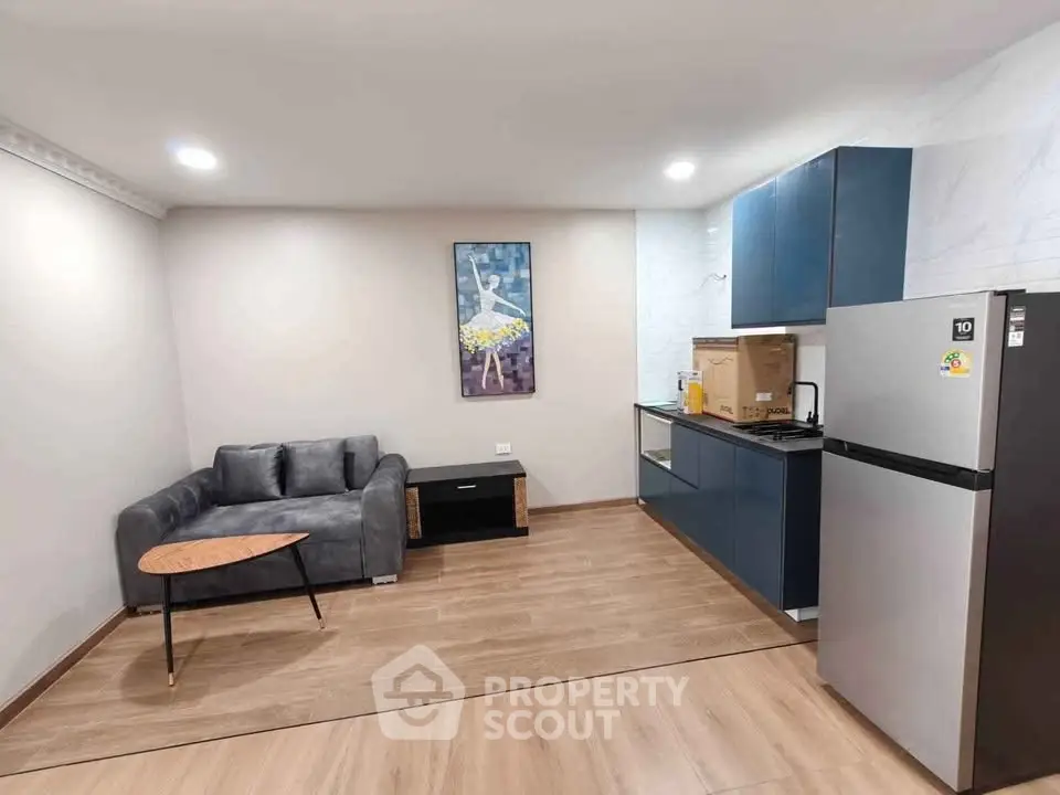 Modern living room with sleek kitchen, featuring stylish furniture and contemporary appliances.