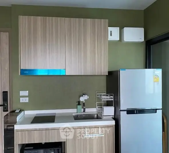 Modern kitchen with sleek cabinetry and compact fridge in stylish apartment.