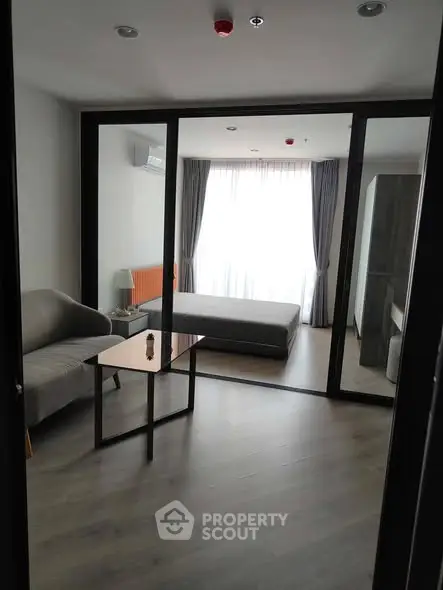 Modern studio apartment with glass partition, cozy living area, and natural light.