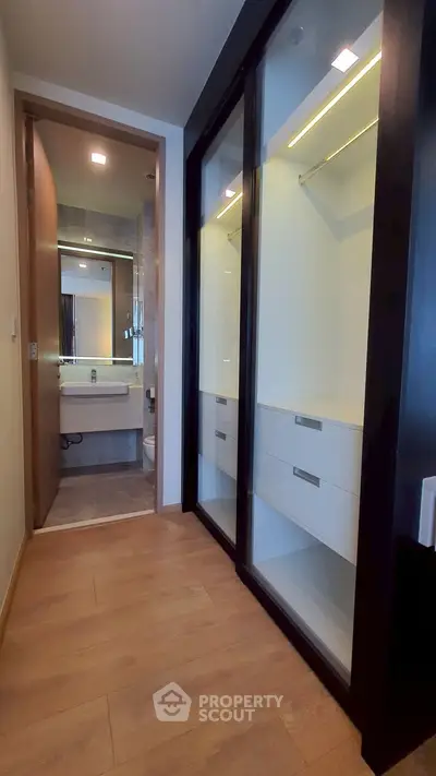 Modern hallway with built-in closet leading to a sleek bathroom