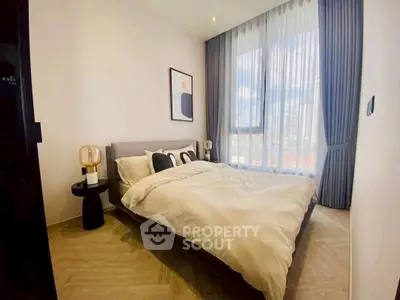 Modern bedroom with large window and stylish decor in a high-rise apartment.