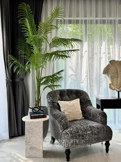 Elegant living room with plush armchair, marble side table, and lush indoor plant.