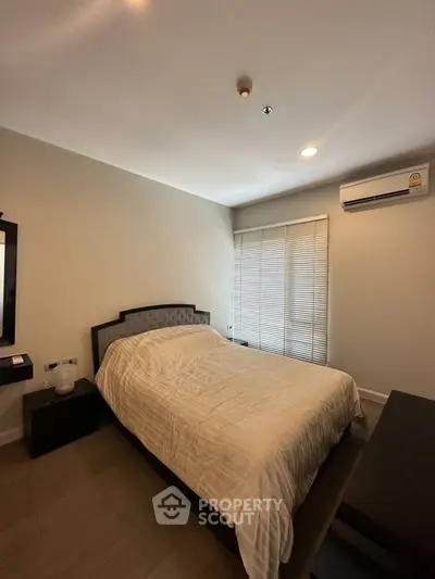 Cozy bedroom with modern decor and natural light, featuring a comfortable bed and air conditioning.
