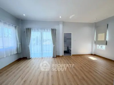 Spacious empty room with large windows and wooden flooring, perfect for customization.