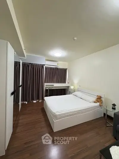 Spacious modern bedroom with wooden flooring and cozy ambiance