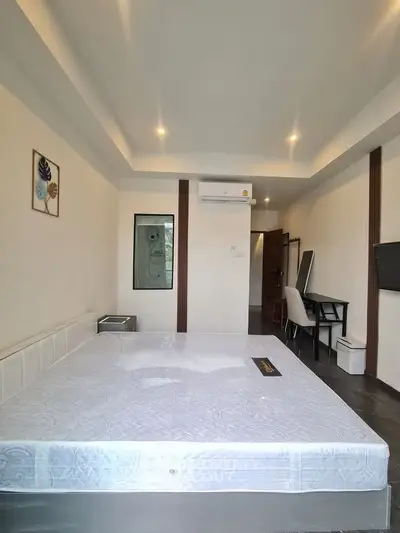 Spacious bedroom with modern decor and ample natural light, featuring a comfortable bed and stylish furnishings.