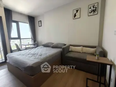 Modern bedroom with large window and cozy seating area in stylish apartment.