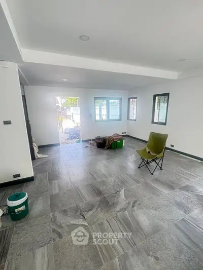 Spacious modern living room with large windows and sleek tile flooring, perfect for natural light lovers.