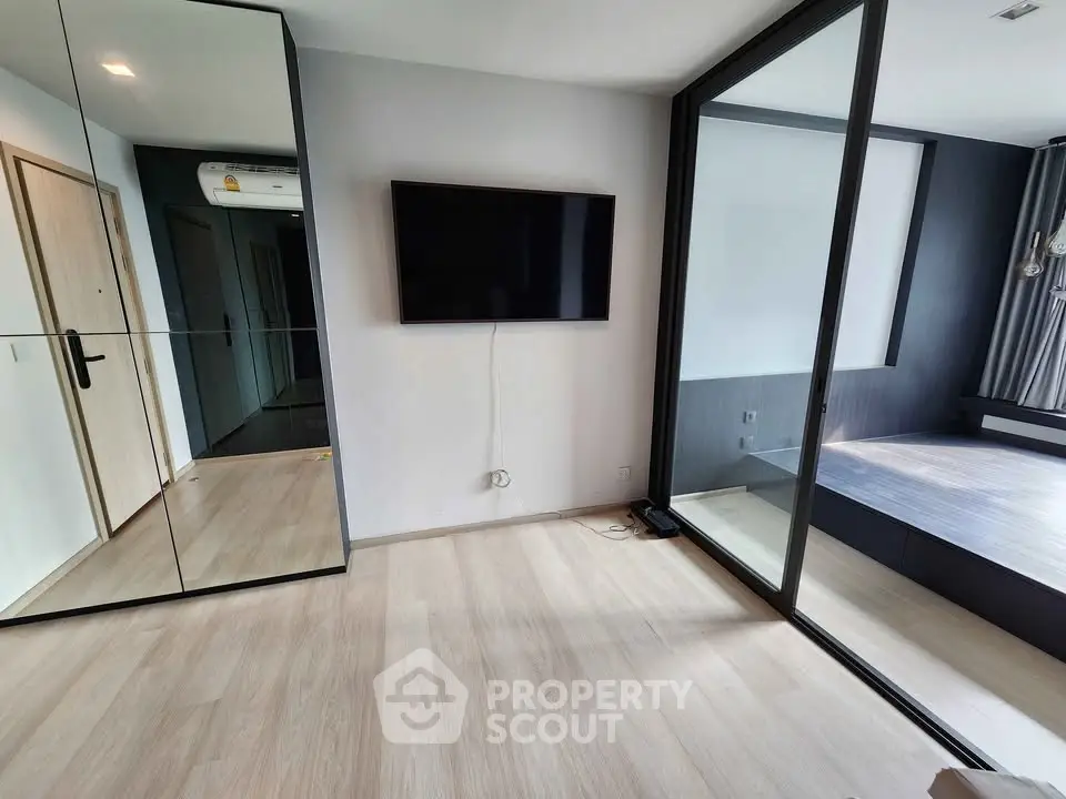 Modern minimalist living room with mirrored closet and wall-mounted TV