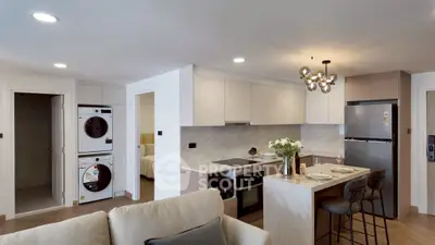 Modern open-plan kitchen with sleek appliances and stylish lighting in a cozy apartment setting.