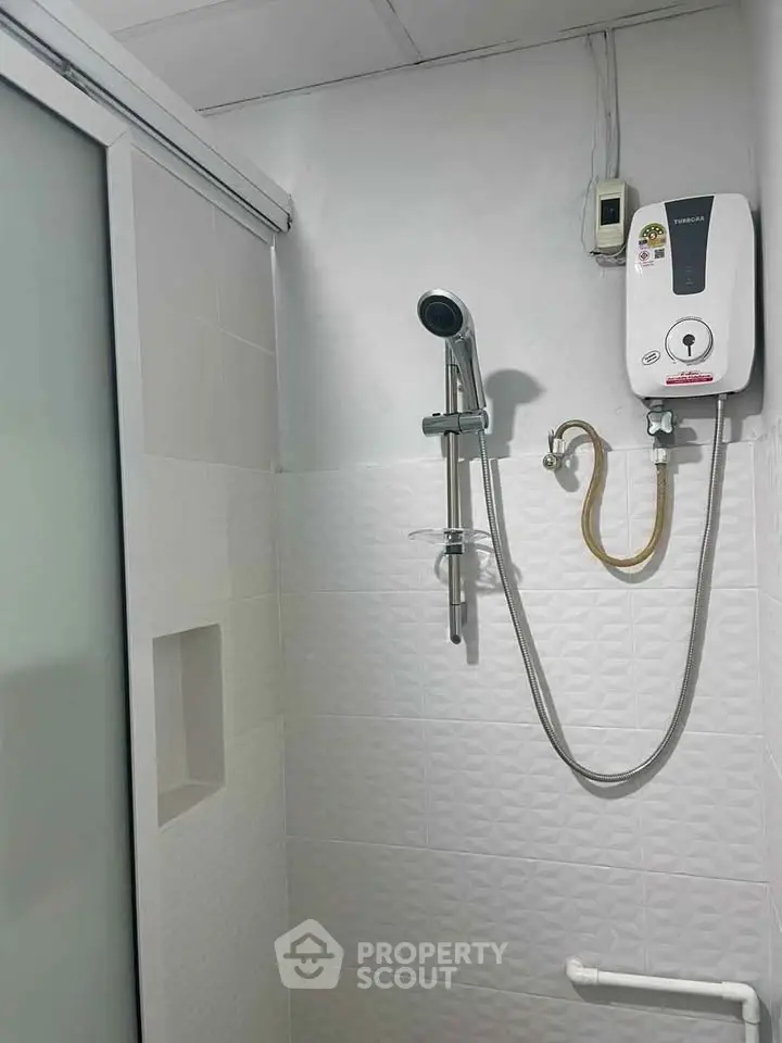 Compact bathroom with modern shower and water heater in minimalist design.