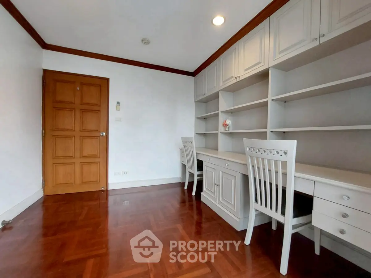 Spacious study room with elegant wooden flooring and built-in shelves