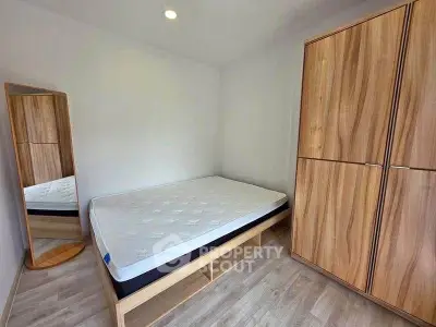 Spacious bedroom with modern wooden wardrobe and comfortable bed in a bright, minimalist design.