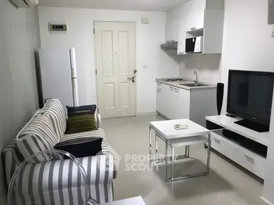 Modern compact living room with integrated kitchen, featuring sleek white cabinetry and cozy striped sofa.