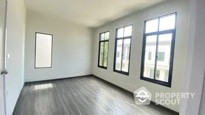 Bright empty room with large windows and modern flooring in a new home