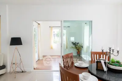 Bright dining area with modern decor and glass doors leading to a sunlit room.