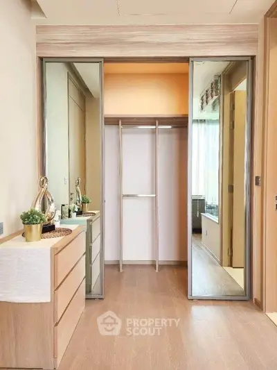 Spacious walk-in closet with mirrored sliding doors and wooden flooring in modern apartment.