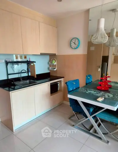 Modern kitchen with sleek cabinets and dining area, featuring stylish lighting and contemporary decor.