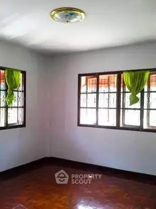 Spacious empty room with large windows and wooden flooring, perfect for customization.